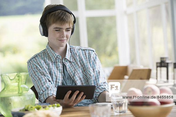 Ein kleiner Junge  der Musik hört und ein digitales Tablet benutzt.