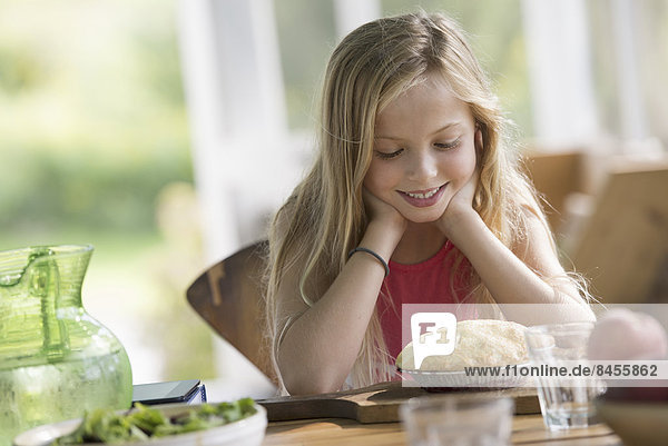 Ein junges Mädchen schaut lächelnd auf einen Kuchen.