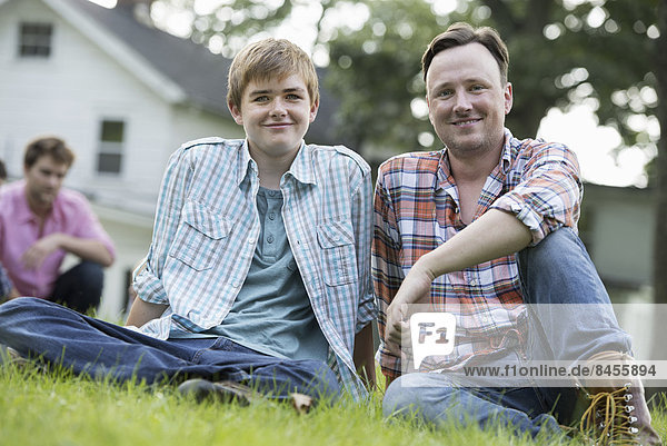 A father and son at a summer party  sitting on the grass.