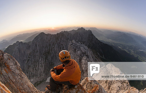 Climber sitting on the top of Ellmauer Halt at sunrise  Ellmau  Wilder Kaiser  North Tyrol  Austria