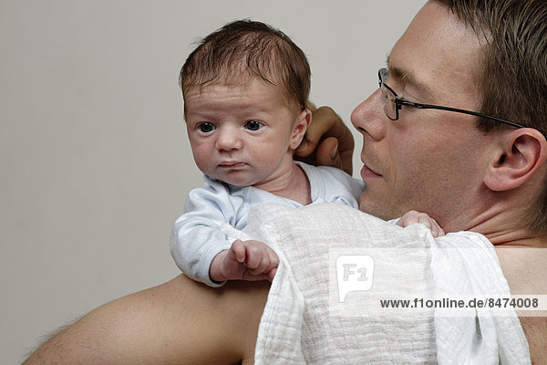 Drei Wochen alter Säugling  Junge wird von seinem Vater über der Schulter gehalten  mit Spucktuch