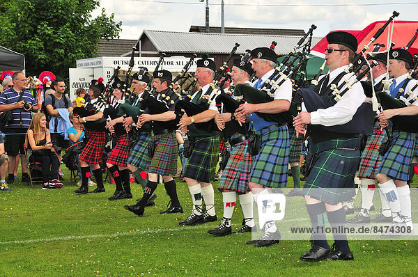 Pipe Band in perfekter Formation auf dem Sportplatz bei den Highland Games  Dufftown  Moray  Highlands  Schottland  Großbritannien