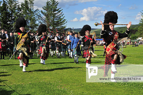 Pipe Band angeführt von mehreren Pipe Majors auf dem Sportplatz bei den Highland Games  Dufftown  Moray  Highlands  Schottland  Großbritannien