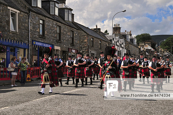 Die Pipe Band  angeführt vom Pipe Major  zieht im Gleichschritt durch die Ortschaft  Dufftown  Moray  Highlands  Schottland  Großbritannien