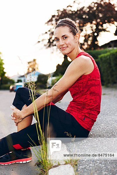 Woman in workout clothes sitting on the curb