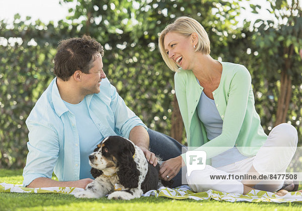 Couple with dog relaxing on grass