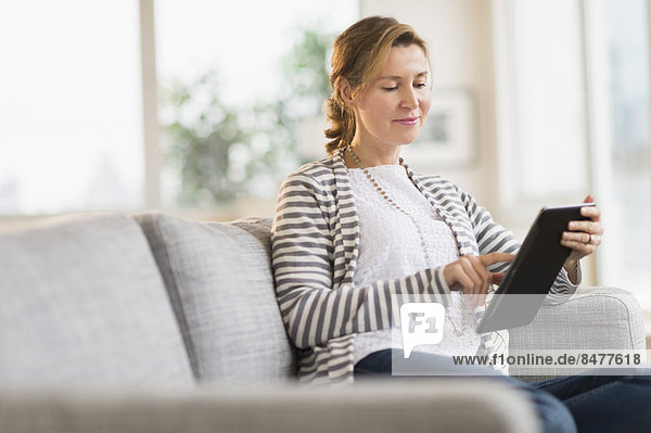 Woman sitting on sofa using tablet pc