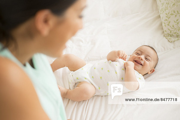Mother looking at baby (2-5 months) lying on bed