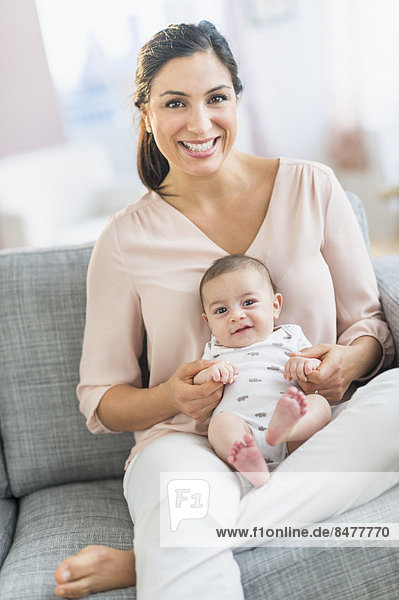 Mother with baby boy (2-5 months) sitting on sofa