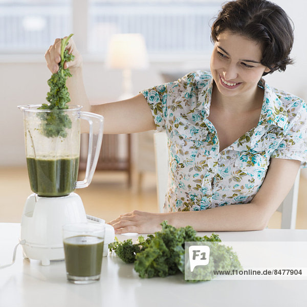 Woman preparing healthy drink with kale