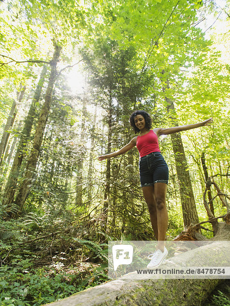 Young woman walking on log in forest