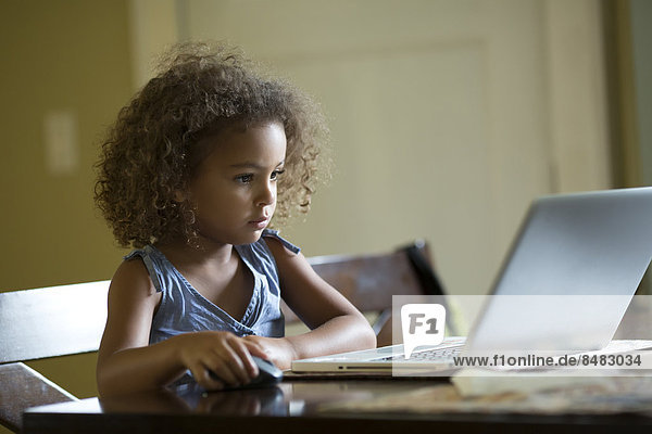 Mixed race girls using laptop at table