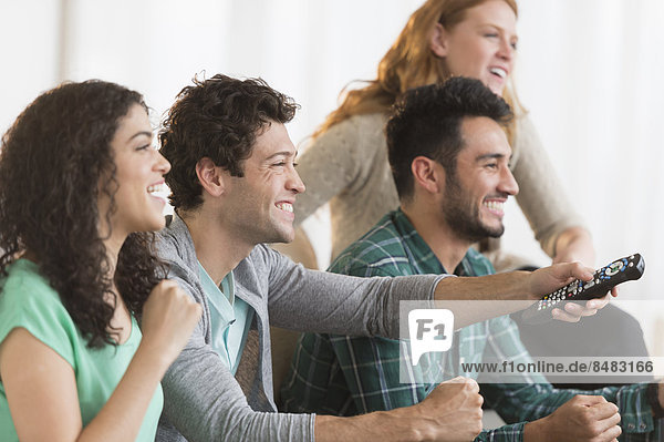 Friends watching television together on sofa