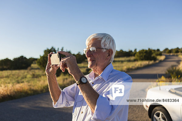 Senior Caucasian man taking pictures with cell phone