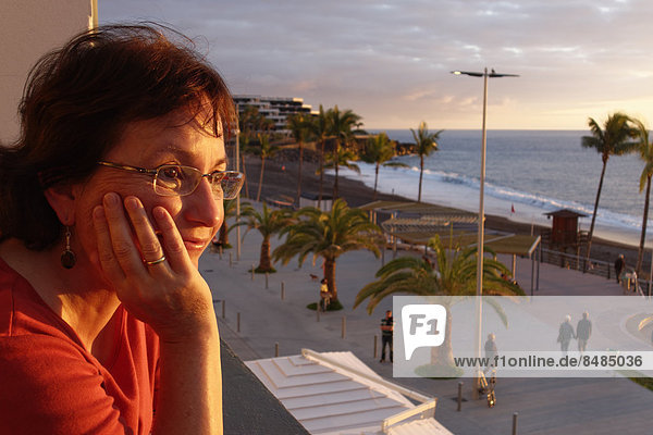 Frau blickt von Balkon ¸ber Promenade  Puerto Naos  La Palma  Kanarische Inseln  Spanien