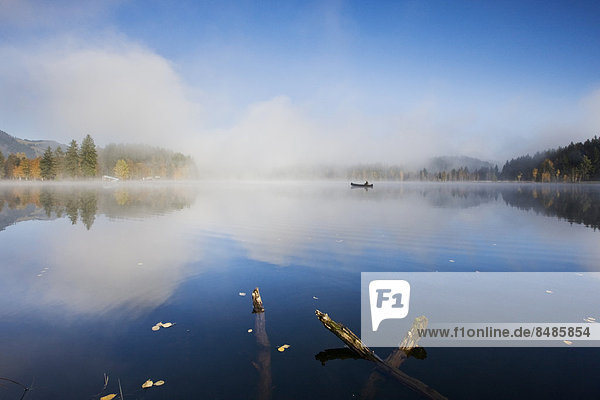 Schwarzsee with fishing boat in the morning mist  Kitzbuehel  Tyrol  Austria  Europe