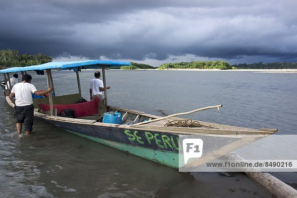 Dark clouds and tourist boat on the Manu river  Manu National Park  UNESCO World Heritage Site  Peru  South America