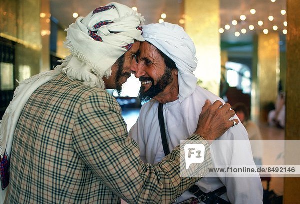 Two men wearing arab headdresses giving the traditional arab greeting in the Hilton Hotel at Al Ain  Abu Dhabi  United Arab Emirates