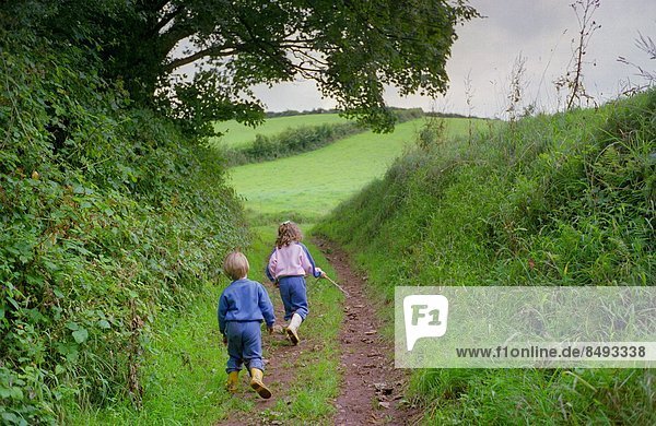 A five year oldgirl and four year old boy walking together in Devon