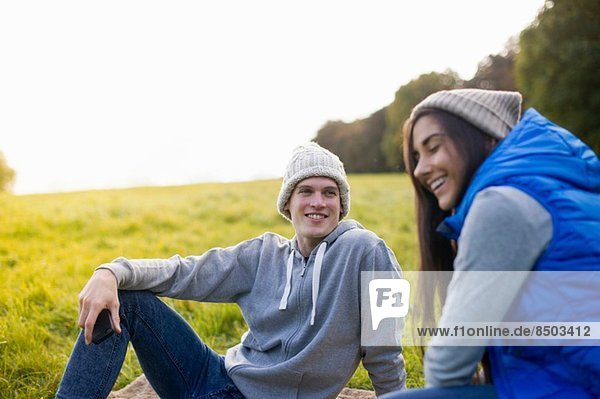 Junges Paar auf Gras sitzend lachend