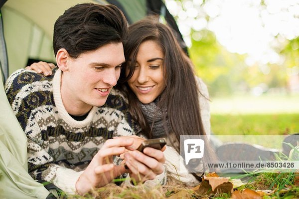 Young couple in tent using smartphone