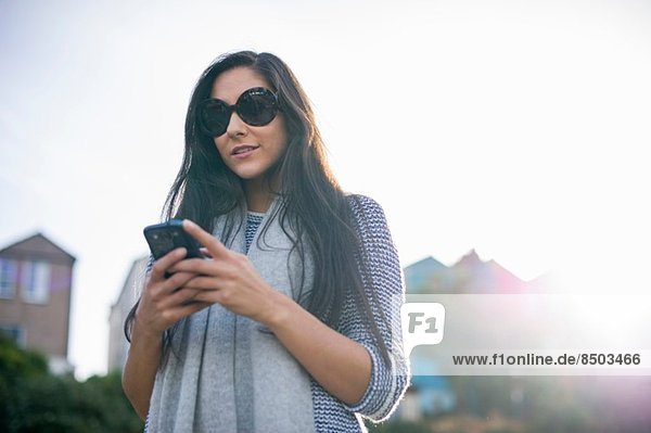 Young woman wearing sunglasses using smartphone