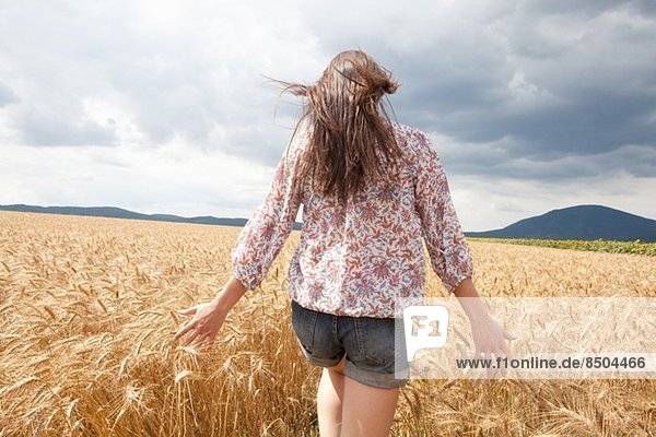 Mid adult woman walking through wheat field