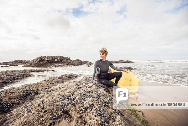 Reife Bodyboarderin auf Felsen sitzend  Devon  UK