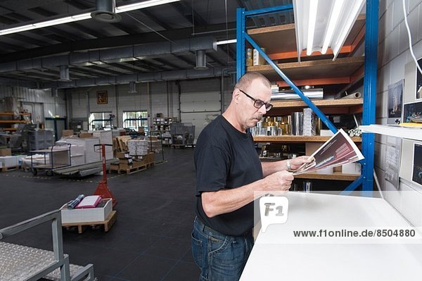Worker checking quality of print products in printing workshop