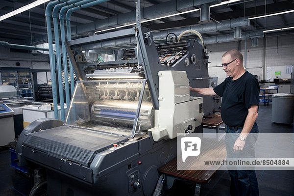 Arbeiter bedient Druckmaschine in der Druckerei