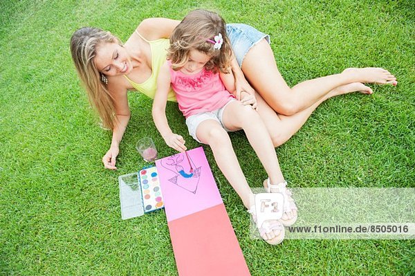 Mutter und Tochter malen  auf Gras sitzend