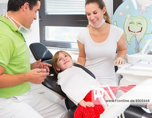 Mädchen im Zahnarztstuhl mit Zahnarzt und Zahnarzthelferin