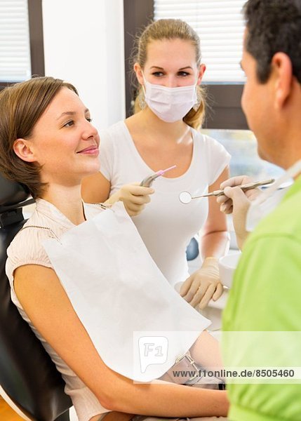 Frau  die sich beim Zahnarzt und der Zahnarzthelferin untersuchen lässt