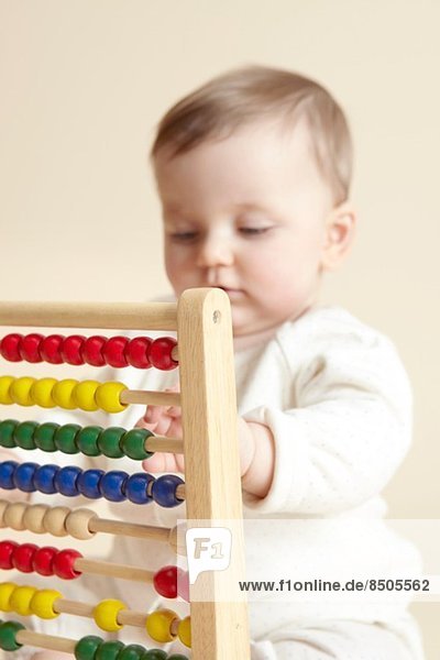 Close up studio portrait of baby girl playing with abacus