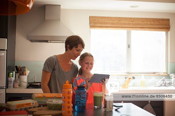 Mother and daughter looking at digital tablet in kitchen