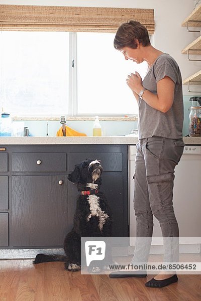 Mature woman and her pet dog in kitchen
