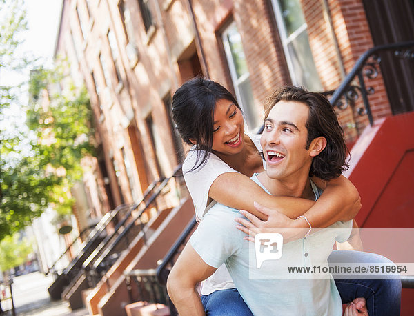 Man carrying girlfriend piggyback outside brownstones