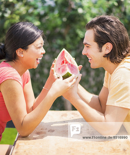 Couple sharing watermelon slice outdoors