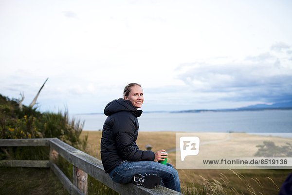 junge Frau junge Frauen Fröhlichkeit sitzend lächeln Küste Insel Blick in die Kamera Ansicht Geländer