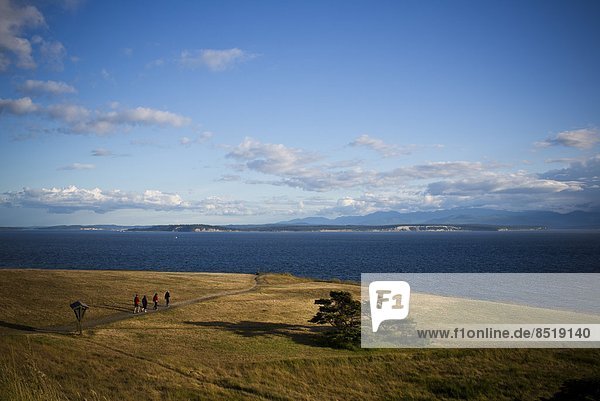 A family hikes on a trail while enjoying the views off the coast of Whidbey Island from Ebey State Park.