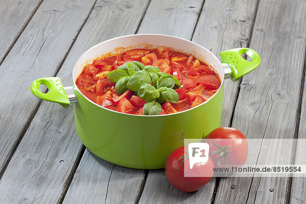 Kochtopf mit Tomatenstücken und Basilikum