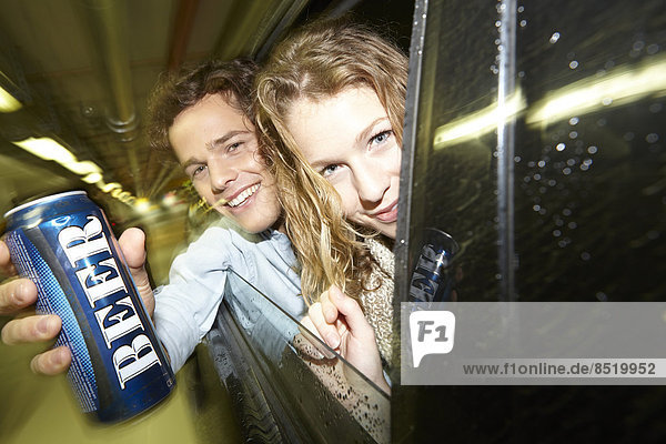 Young couple on the moße showing beer can