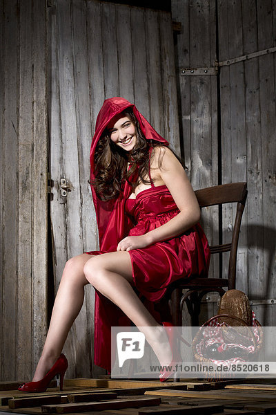 Junge Frau sitzend in einer Hütte als Rotkäppchen verkleidet  Studioaufnahme