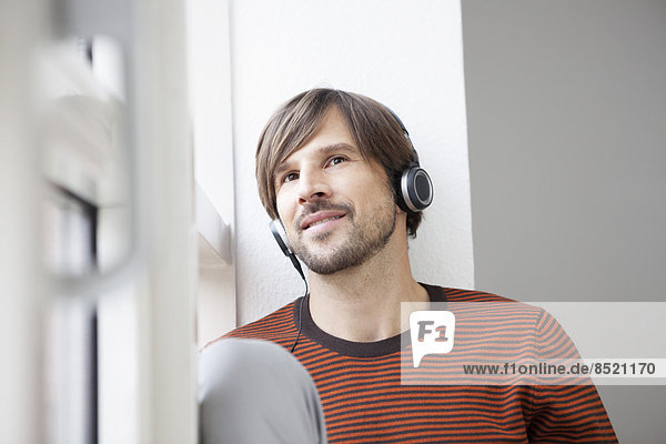 Man sitting at window  wearing head phones