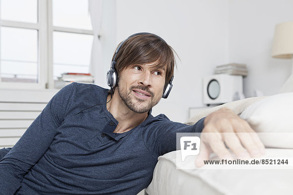 Man sitting on sofa  wearing head phones
