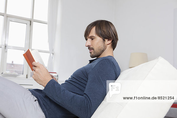Mann auf Sofa sitzend  Lesebuch