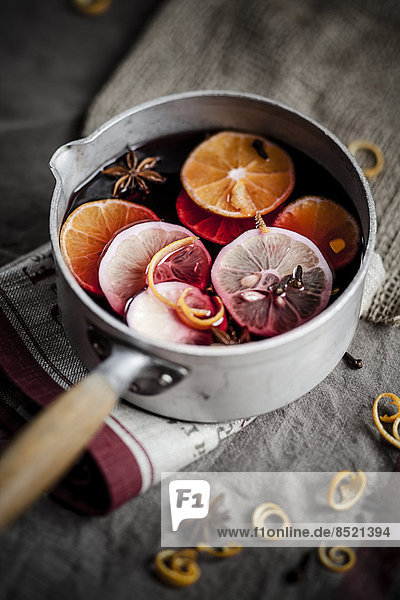 Casserole with mulled wine  slices of lemons and oranges and spices