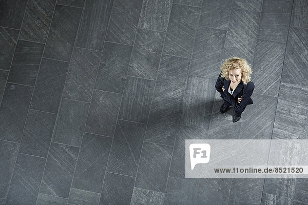 Junge Geschäftsfrau steht auf dem Boden und schaut nach oben.