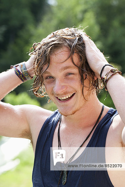 Laughing young man with hands on his wet hair