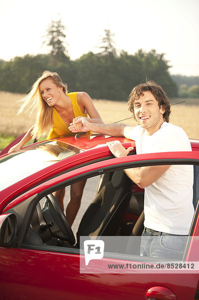 Junges Paar mit rotem Auto
